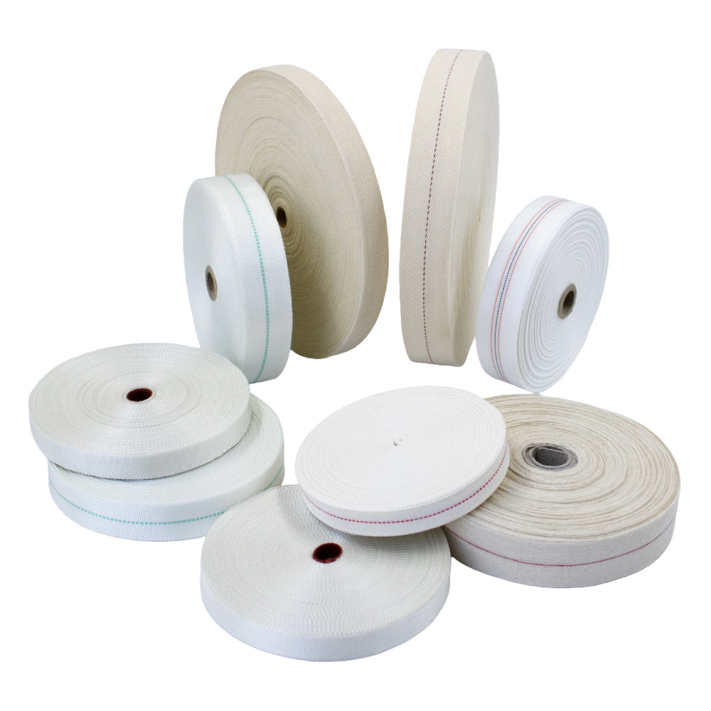 Assorted rolls of electrical non-adhesive tape in various materials, colours, and sizes, stacked and upright on a pale background—includes woven glass, cotton webbing, and polyester tapes for electrical insulation applications.